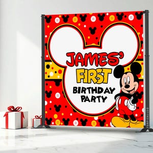 May include: A red backdrop with a Mickey Mouse theme, featuring the text "JAMES' FIRST BIRTHDAY PARTY." The design includes Mickey Mouse ears, polka dots, and a cartoon image of Mickey Mouse. Two white gift boxes with red ribbons are in the foreground.