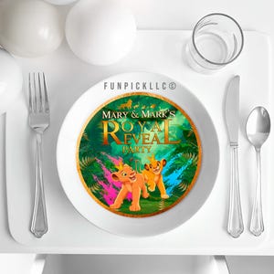 Puede incluir: Un plato de cerámica blanco con un borde dorado que presenta un diseño colorido de El Rey León. El plato tiene el texto "Mary & Mark's Royal Reveal Party" e imágenes de Simba y Nala. Un tenedor, un cuchillo y una cuchara están a la derecha.