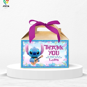 May include: A tan gift box with a purple ribbon and handle. The front features a blue border with the character Stitch holding a guitar, and the words "THANK YOU" with additional text. The box is on a white pedestal.