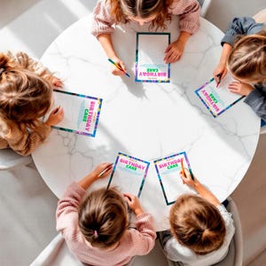A group of children sitting around a table, engaged in drawing and coloring birthday cards.