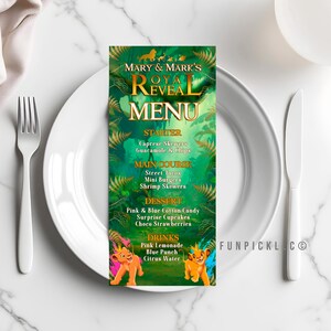 May include: A vertical menu card with a green jungle theme, featuring the text "Mary & Mark's Royal Reveal Menu." The menu lists starters, main courses, desserts, and drinks. Two cartoon lion cubs are at the bottom. The card is on a white plate.