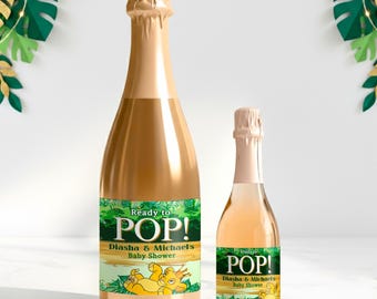 Puede incluir: Dos botellas de champán, una grande y otra pequeña, con exteriores dorados. Cada botella tiene una etiqueta que dice "Ready to POP!" y "Diasha & Michael's Baby Shower". Las etiquetas presentan un tema de jungla con un león de dibujos animados.