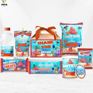 May include: A collection of party favors featuring a Nemo theme. Includes water bottles, juice boxes, a gift box with a bow, chip bags, candy bars, and a can of potato chips. All items are decorated with Nemo and the text "Brycen is turning one."