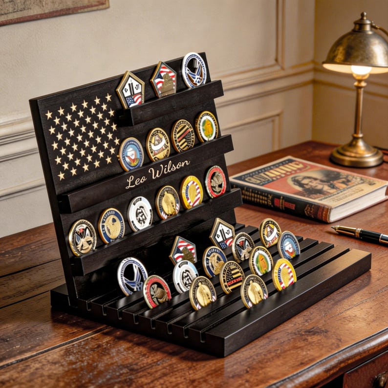 May include: A black wooden coin display stand with an American flag design and the name "Leo Wilson" engraved. The stand holds numerous collectible coins of various shapes and colors, showcasing military and patriotic themes.
