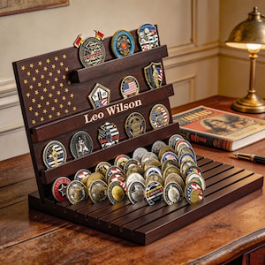 May include: A dark wood coin display case with multiple shelves, holding a collection of coins. The case has a flag design with stars and stripes. The name "Leo Wilson" is displayed on the case.