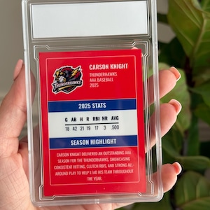 May include: A baseball card encased in a clear plastic holder. The card features the name "Carson Knight" and "Thunderhawks AAA Baseball 2025." Stats include G, AB, H, R, RBI, HR, AVG. The card highlights Knight's outstanding season.