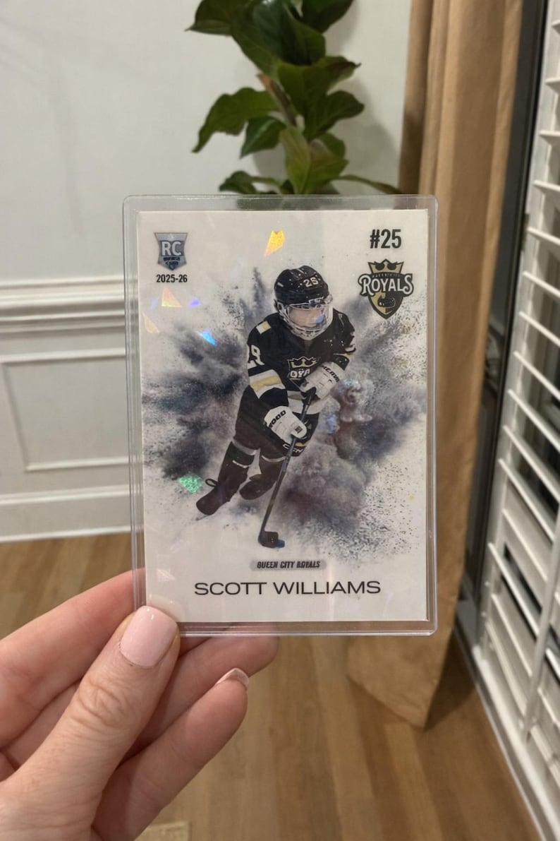 May include: A hockey trading card featuring Scott Williams of the Queen City Royals. The card has a holographic design with the team logo and player's name. The card is encased in a protective sleeve.