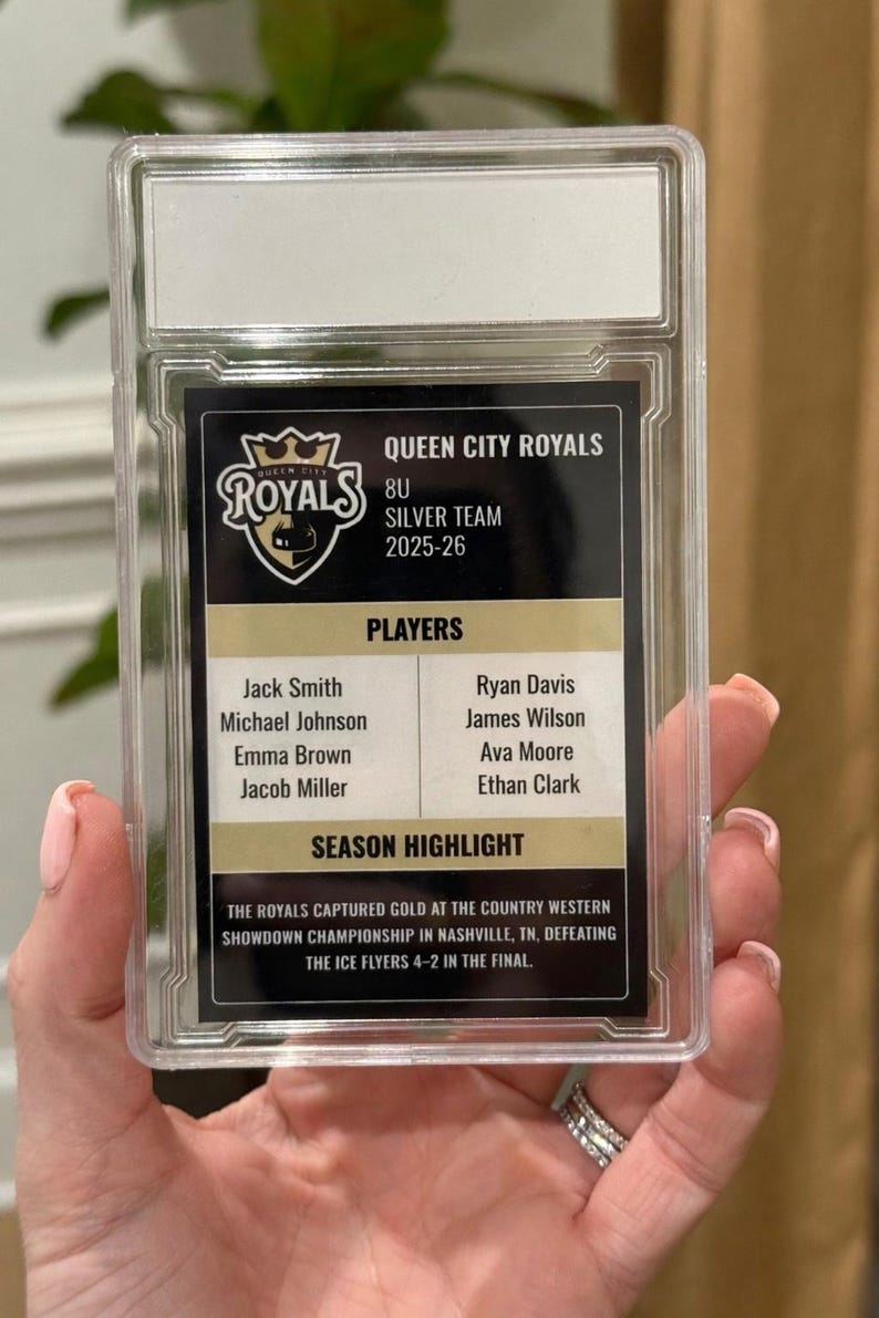 May include: A Queen City Royals hockey card encased in a clear protective holder. The card features the team logo, player names, and season highlights, including their championship win in Nashville, TN.