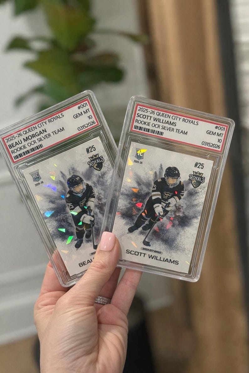 May include: Two graded hockey cards featuring players from the 2025-26 Queen City Royals. One card showcases Beau Morgan, the other Scott Williams. Both cards are graded GEM MT 10, with serial numbers. Each card has a player image.