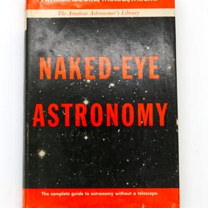 Puede incluir: Un libro antiguo titulado "Naked-Eye Astronomy" con una cubierta negra y texto rojo. La cubierta presenta un fondo estrellado y el nombre del autor. El libro forma parte de "The Amateur Astronomer's Library" y es una guía de astronomía sin telescopio.