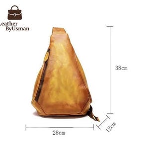 May include: A tan leather sling bag with a zipper closure and a small pocket. The bag is 15 inches tall, 11 inches wide, and 4.7 inches deep. The bag has the text "Leather By Usman" on the top left.