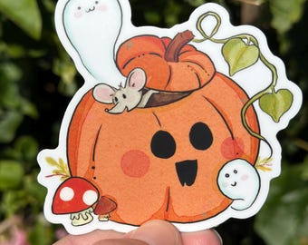 Peut inclure: Un autocollant fantaisiste représentant une citrouille orange souriante avec une souris à l'intérieur. Un fantôme amical flotte à proximité, et un champignon rouge à pois blancs est en bas. Des vignes et des feuilles vertes ajoutent des détails à ce design d'Halloween.