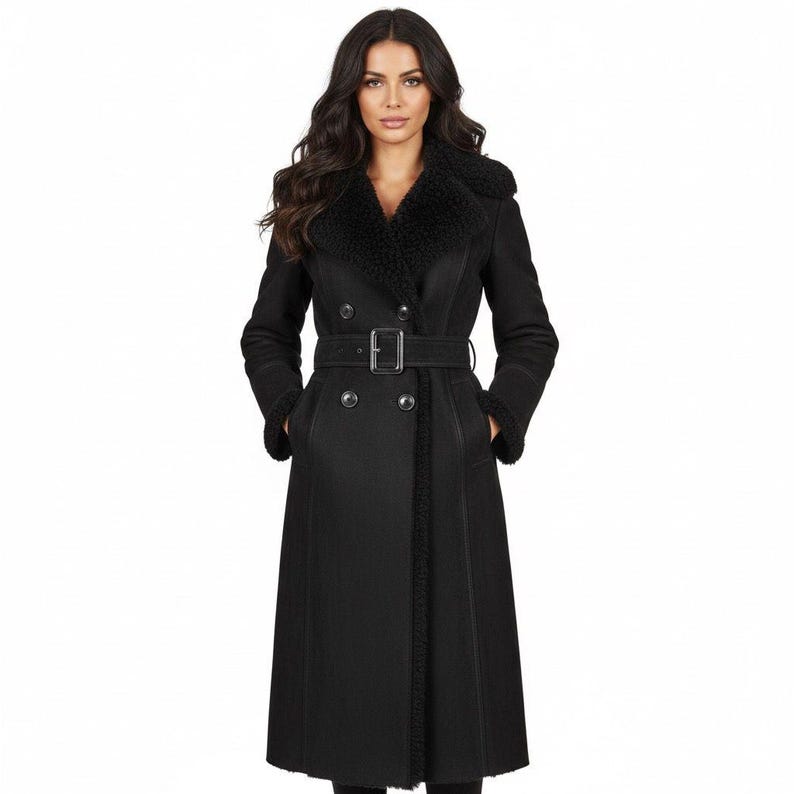 May include: A long, black coat with a faux fur collar and trim. The coat features a double-breasted design, a belt with a silver buckle, and pockets. The coat is a classic style, suitable for cold weather.