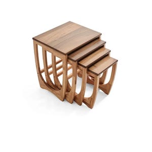 May include: A set of four wooden nesting tables. Each table has a square top and curved legs. The tables are designed to fit inside each other, with the largest table at the base. The wood has a warm, natural finish.
