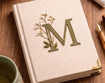 Cuaderno personalizado con inicial botánica M bordada, producto estético de lino.