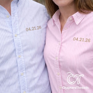 May include: Two button-down shirts, one light blue and one pink, with vertical stripes. Each shirt has the date "04.21.26" embroidered in gold thread. The pink shirt has the "ChaptersThreads" logo.