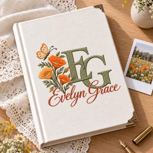 Puede incluir: Un diario de tapa dura blanco con amapolas naranjas bordadas, una mariposa y las letras de monograma EG en verde con el nombre Evelyn Grace cosido en letra cursiva naranja. El libro tiene esquinas decorativas de metal en tono dorado.