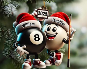 May include: Christmas ornament featuring two cartoon billiard balls. One is black with the number 8, the other is white. Both wear Santa hats with names. One holds a sign with "2025". A pool cue is held by the white ball. Red and white sneakers complete the look.