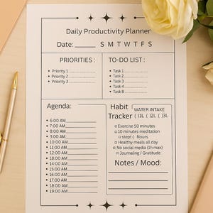 Può includere: Un Daily Productivity Planner bianco con sezioni per priorità, liste di cose da fare, agenda, rilevatore di abitudini e note. Include una penna e una rosa gialla. Il planner ha una sezione per l'assunzione di acqua.