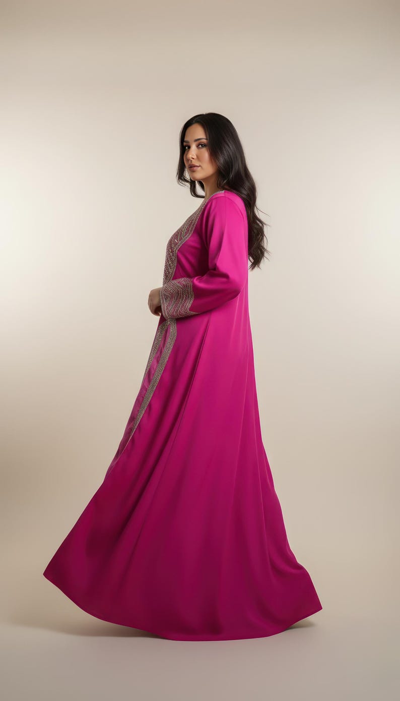 May include: A long, flowing magenta dress with long sleeves. The dress features intricate gold embroidery along the front and sleeves. The garment is made of a smooth, lightweight fabric, suitable for formal occasions.