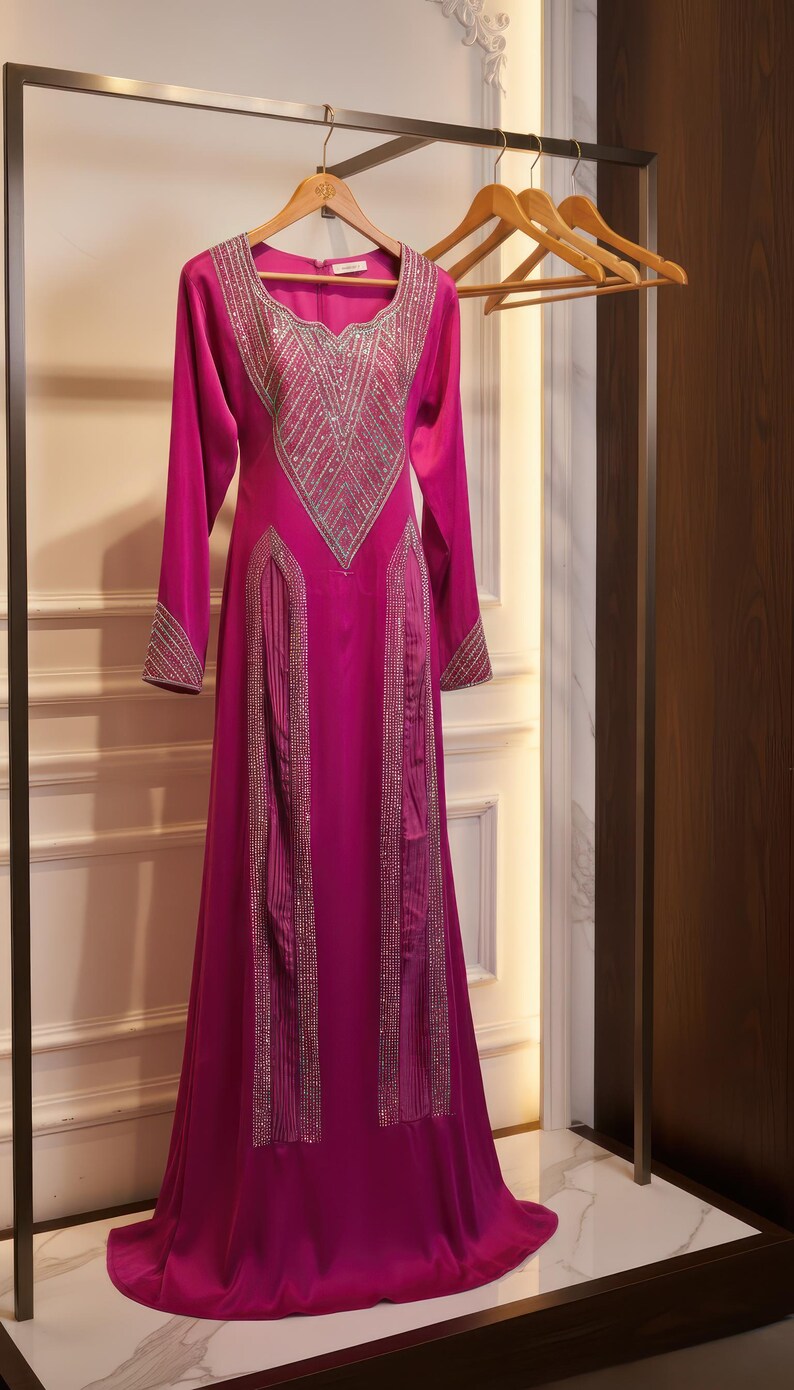May include: A long, fuchsia-colored formal dress with long sleeves and a floor-length skirt. The dress features intricate silver embellishments around the neckline, cuffs, and down the front. It hangs on a wooden hanger.
