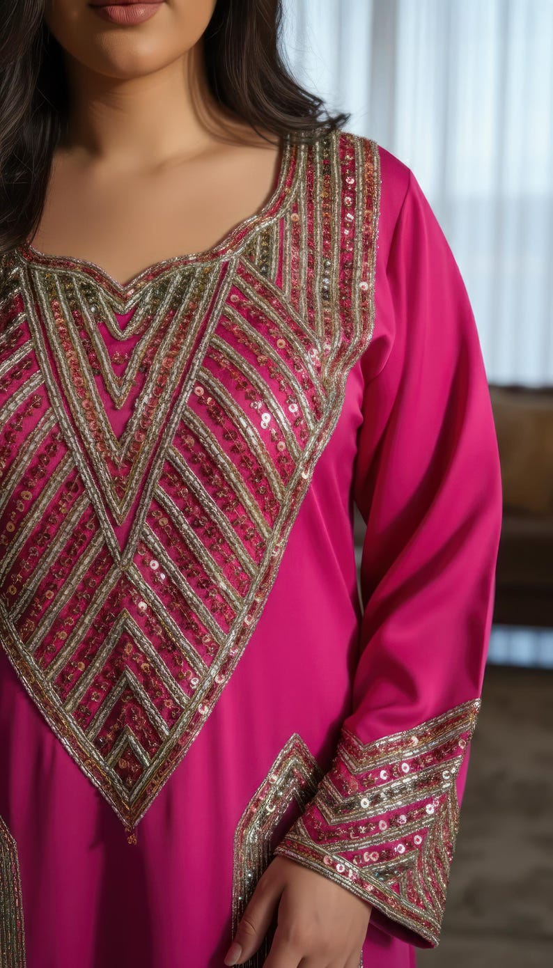 May include: A magenta-colored dress with long sleeves and intricate gold and sequin embellishments. The neckline and cuffs feature detailed geometric patterns. The dress has a flowing, elegant design, suitable for special occasions.