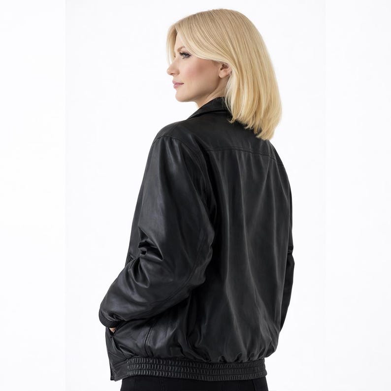 May include: A black leather jacket with a collared neckline and a ribbed hem. The jacket has long sleeves and pockets. The model is wearing the jacket.
