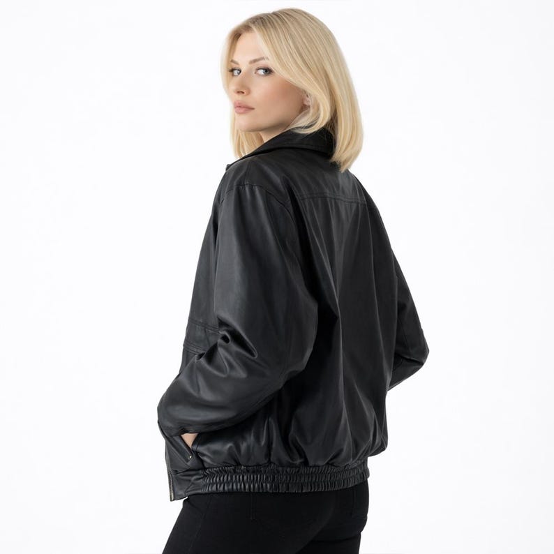 May include: A black leather jacket with a collared neckline and a ribbed hem. The jacket has a classic bomber style with a zipper closure and pockets. The model is wearing black pants.