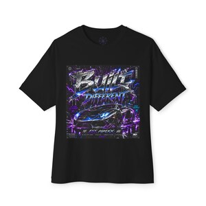 Könnte beinhalten: Schwarzes T-Shirt mit einem grafischen Design, das ein Sportwagen und die Worte "Built Different" in einer stilisierten Schriftart zeigt. Das Design enthält lila und blaue Blitzeffekte und den Text "EST MMXX".