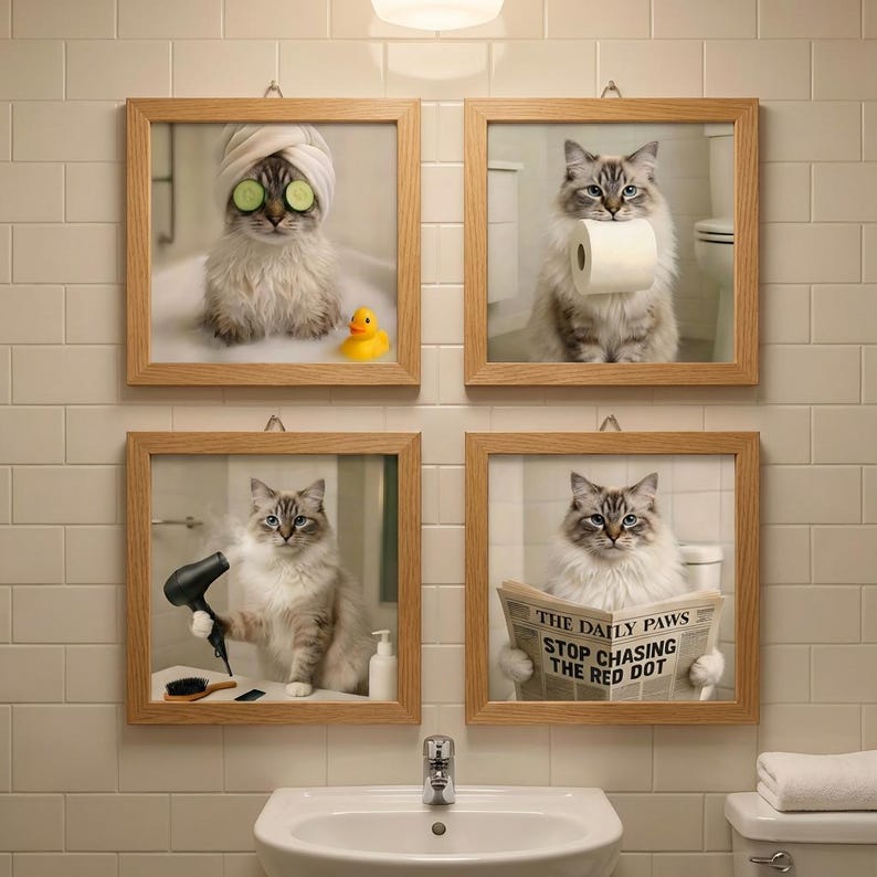May include: Four framed prints of cats in a bathroom setting. One cat has cucumber slices on its eyes and a towel on its head. Another holds toilet paper, a third uses a hairdryer, and the last reads a newspaper with the headline "THE DAILY PAWS STOP CHASING THE RED DOT."