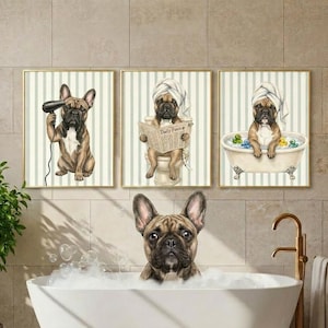 K&ouml;nnte beinhalten: Drei gerahmte Kunstdrucke mit franz&ouml;sischen Bulldoggen in einem Badezimmer. Einer der Hunde f&ouml;hnt sich, ein anderer liest Zeitung, und der dritte sitzt in einer Badewanne. Die Drucke haben goldene Rahmen und einen gestreiften Hintergrund.