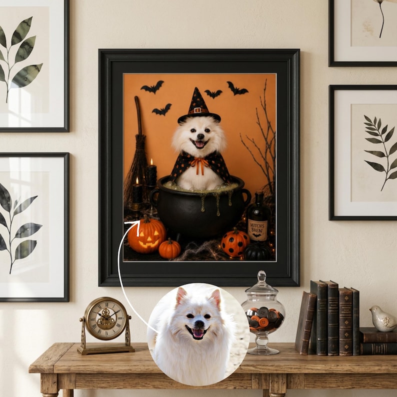 May include: A framed wall art print featuring a white dog wearing a black witch hat and cape, sitting inside a black cauldron. The scene includes orange pumpkins, a broomstick, and bats against an orange background. A circular inset shows the dog.