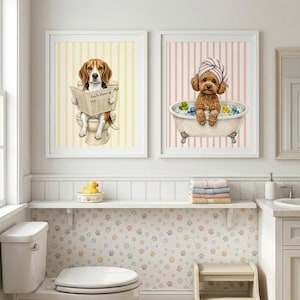 K&ouml;nnte beinhalten: Zwei gerahmte Kunstdrucke f&uuml;r die Badezimmerdekoration. Einer zeigt einen Beagle, der auf einer Toilette Zeitung liest, der andere einen Pudel in einer Badewanne mit einem Handtuch. Beide haben einen gestreiften Hintergrund. Die Zeitung tr&auml;gt den Titel "Daily Paws".