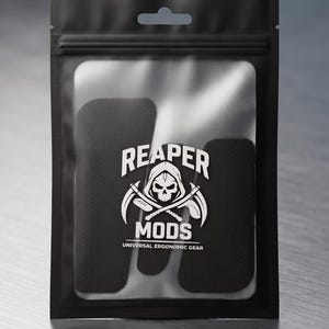 May include: A black resealable plastic pouch containing black adhesive grip tape pieces. The front of the pouch features a white logo with a skull wearing a hood, crossed scythes, and the text REAPER MODS UNIVERSAL ERGONOMIC GEAR printed in white.