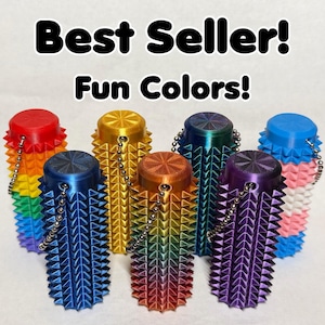 May include: A collection of colorful, spiked bottle stoppers in various shades, including red, blue, gold, and rainbow gradients. Each stopper has a chain. Text reads "Best Seller! Fun Colors!"