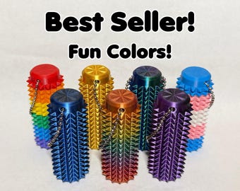 May include: A collection of colorful, spiked bottle stoppers in various shades, including red, blue, gold, and rainbow gradients. Each stopper has a chain. Text reads "Best Seller! Fun Colors!"