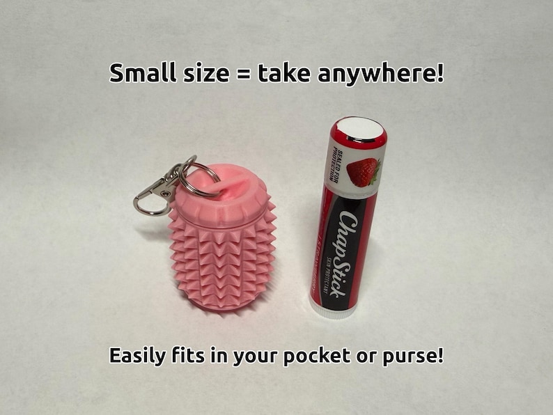 May include: A pink cylindrical silicone container with a textured spiked surface and a metal keychain ring, positioned next to a red and black ChapStick lip balm tube. The text reads: Small size = take anywhere! Easily fits in your pocket or purse!