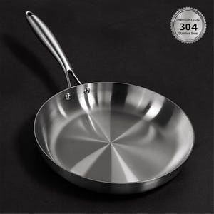Può includere: Una padella in acciaio inossidabile con un lungo manico. La padella ha un interno ed esterno lucidi, che riflettono la luce. Il testo "Premium Grada 304 Stanties Sreel" è stampato su un distintivo d'argento.