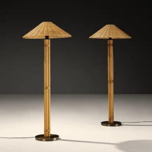 May include: Two bamboo floor lamps with woven shades. The lamps have a natural wood finish and a circular base. The shades are a light tan color and are square-shaped. The lamps are on a white surface.