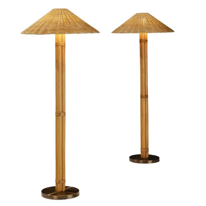 May include: Two bamboo floor lamps with woven shades. The lamps have a natural wood finish and a round, dark metal base. The shades are square and angled, providing a warm, ambient light. The lamps are designed for indoor use.