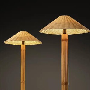 May include: Two bamboo floor lamps with woven, conical shades. The lamps have a natural, light brown color and emit a warm, inviting glow. The lamps are set against a dark background, highlighting their design.