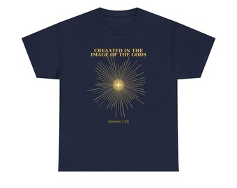 Könnte beinhalten: Marineblaues T-Shirt mit goldenem Text und Grafik. Der Text lautet "CREATED IN THE IMAGE OF THE GODS" über einem goldenen Burst-Design mit einem zentralen Kreuz. Darunter steht "Genesis 1:26".