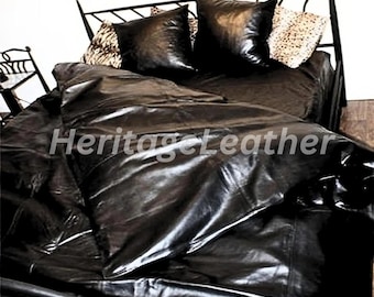 May include: Black leather bedding set on a wrought iron bed frame. The set includes a comforter, pillowcases, and decorative pillows with a leopard print. The text "Heritage Leather" is visible on the comforter.