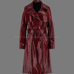 May include: A red snakeskin-effect trench coat with a double-breasted design. The coat features a belt at the waist, a notched collar, and pockets. The coat is a long length and has a classic trench coat silhouette.