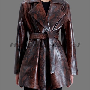 May include: A brown snakeskin-effect coat with a belted waist. The coat has a classic lapel collar and long sleeves. The glossy finish and detailed pattern create a sophisticated look. The coat is knee-length.