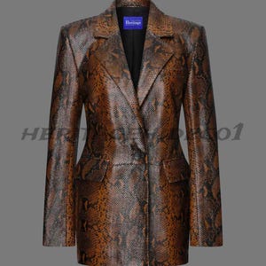 Pode incluir: Um blazer castanho e preto com padrão de pele de cobra, com lapela entalhada, dois bolsos frontais e fecho de um botão. O blazer tem mangas compridas e um interior preto. A palavra "Heritage" está numa etiqueta azul.