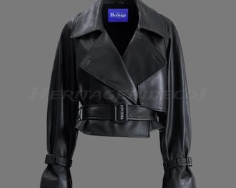 May include: Black leather jacket featuring a wide collar, wrap-style front, and a belted waist. The jacket has long sleeves with buckle details at the cuffs. The word "Heritage" is visible on a blue label.