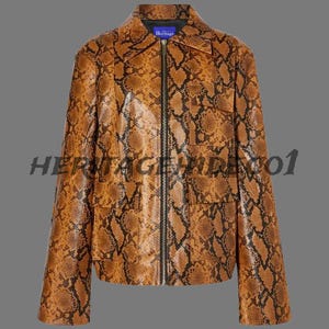 Peut inclure: Veste marron et noire à motif peau de serpent, avec fermeture éclair et deux poches avant. La veste a un col et des manches longues. Le mot "Heritage" est imprimé sur une étiquette bleue près du col.