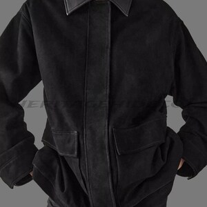 May include: A black jacket with a leather collar and accents. The jacket has two large front pockets and a vertical leather strip down the center. The sleeves are cuffed, and the jacket appears to be made of a soft material.