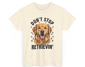 Puede incluir: Camiseta color crema con una ilustración de un golden retriever sonriente. El texto "DON'T STOP RETRIEVEIN'" está impreso en negro encima y debajo de la cabeza del perro, con huellas de patas.